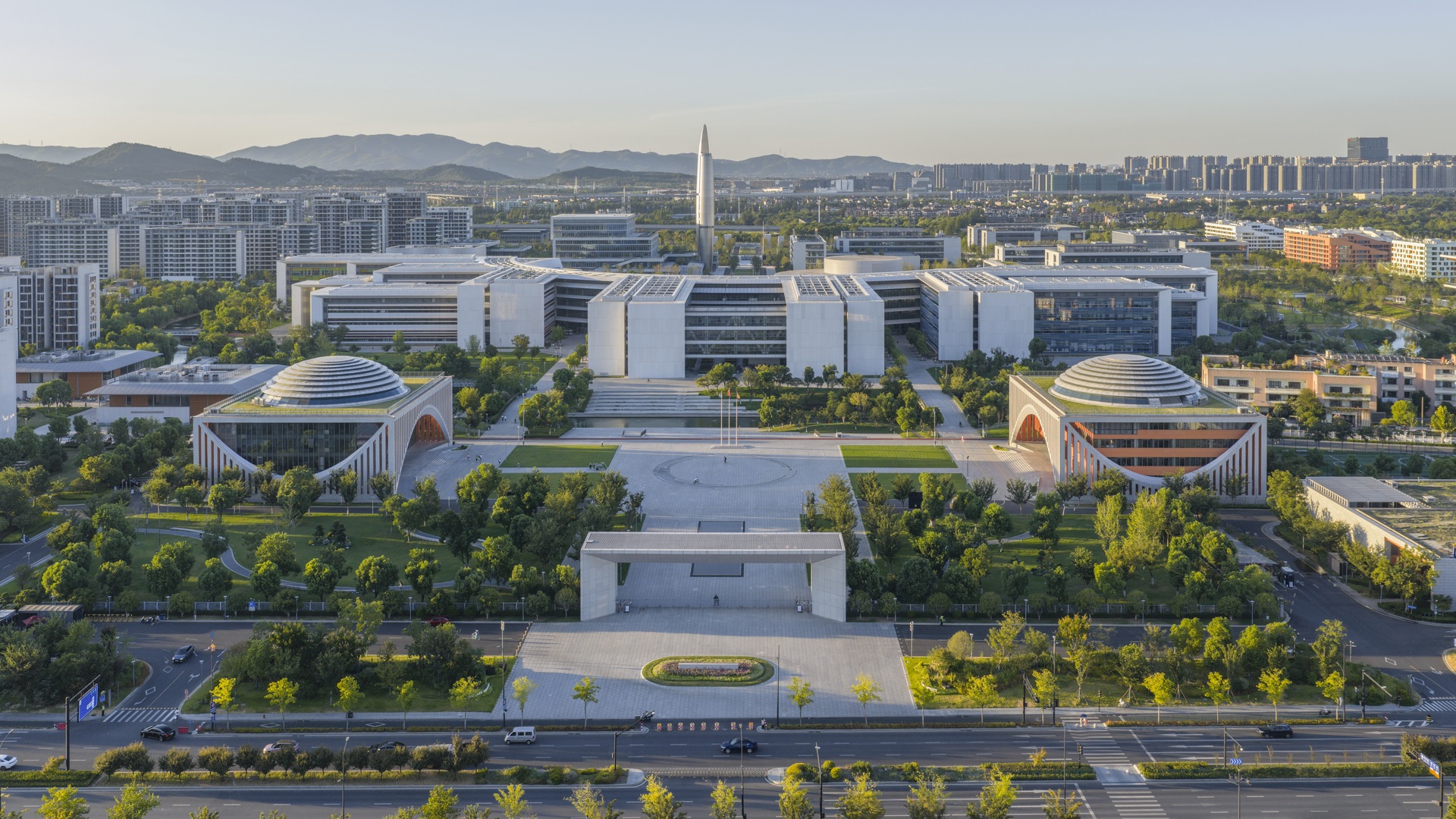 Luftaufnahme eines Hightech-Campus mit innovativen, umweltfreundlichen Gebäuden und Kuppelbauten in einem landschaftlich gestalteten, nachhaltigen Gelände.