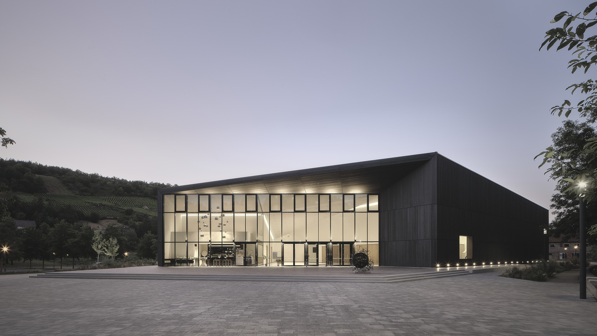 Eine moderne industrielle Forschungseinrichtung mit einer präzise gefertigten Glasfassade, die in der Abenddämmerung beleuchtet wird und ein Beispiel für nachhaltiges und zukunftsweisendes architektonisches Design darstellt.